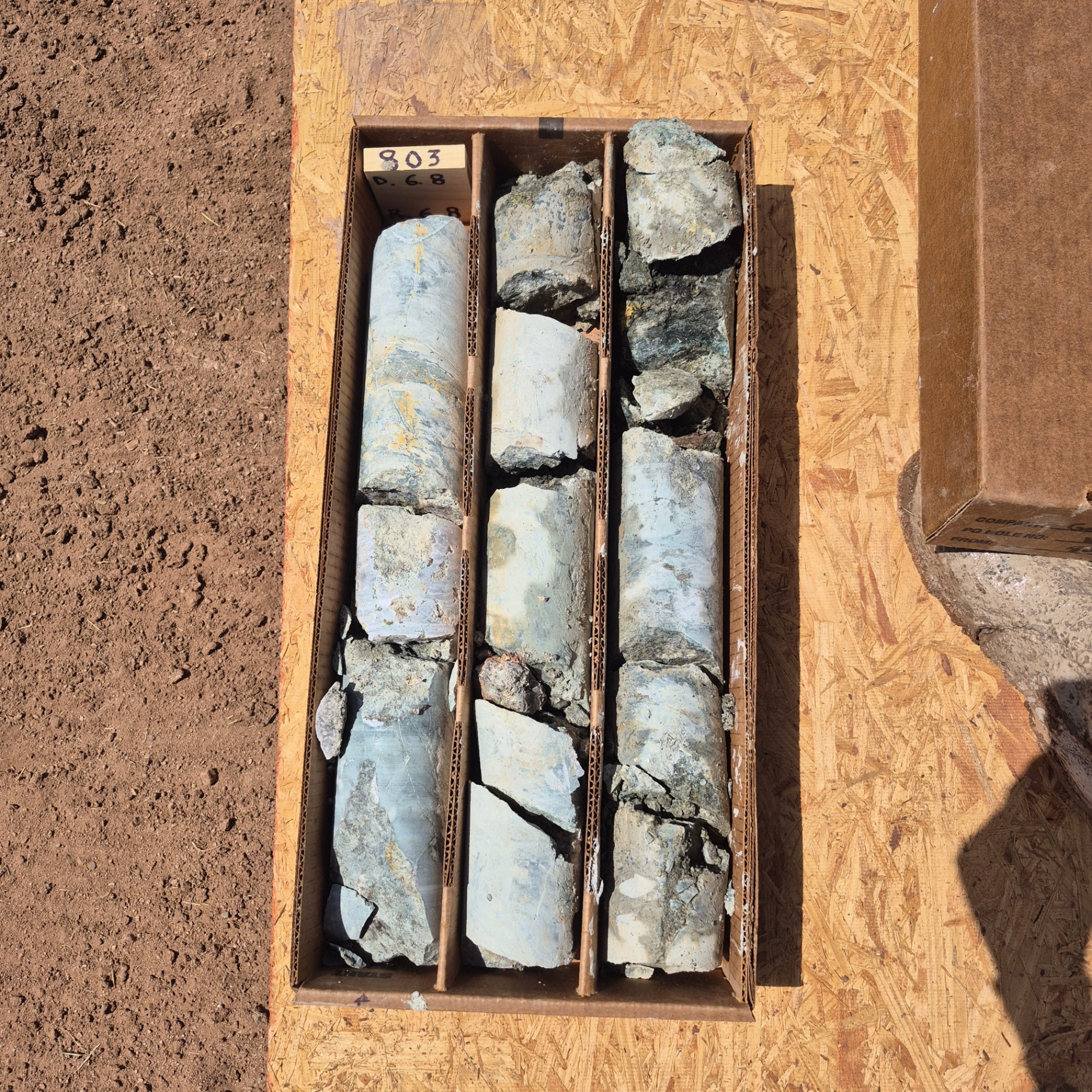 Boxed drill core laid out and depth-marked at the drill site